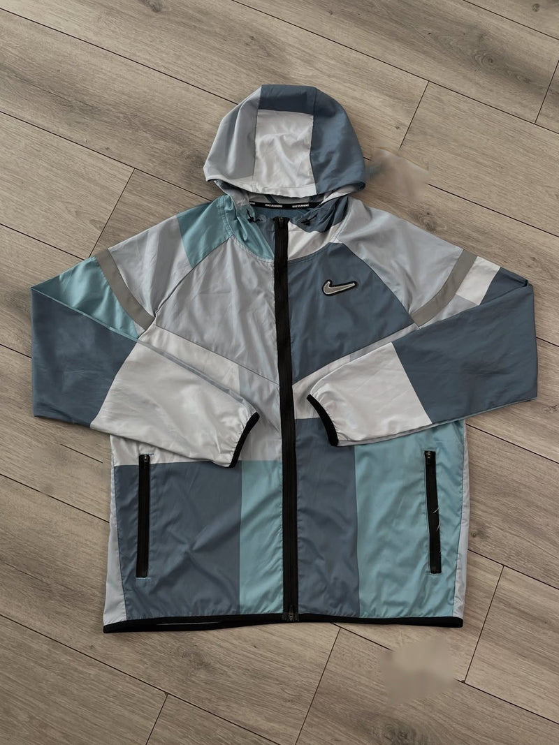 Veste coupe-vent Nike Wild Run bleu gris et turquoise dépliée, zip intégral et poches zippées visibles
