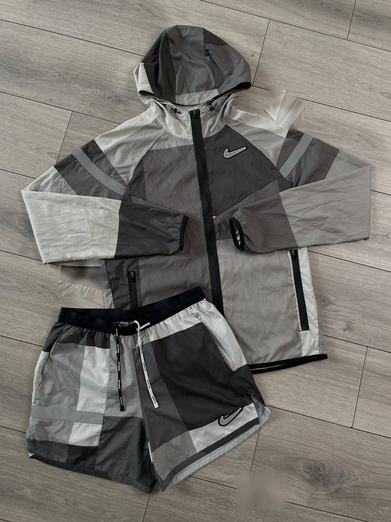 Ensemble running Nike Wild Run gris et blanc : veste coupe-vent à capuche et short assorti posés à plat