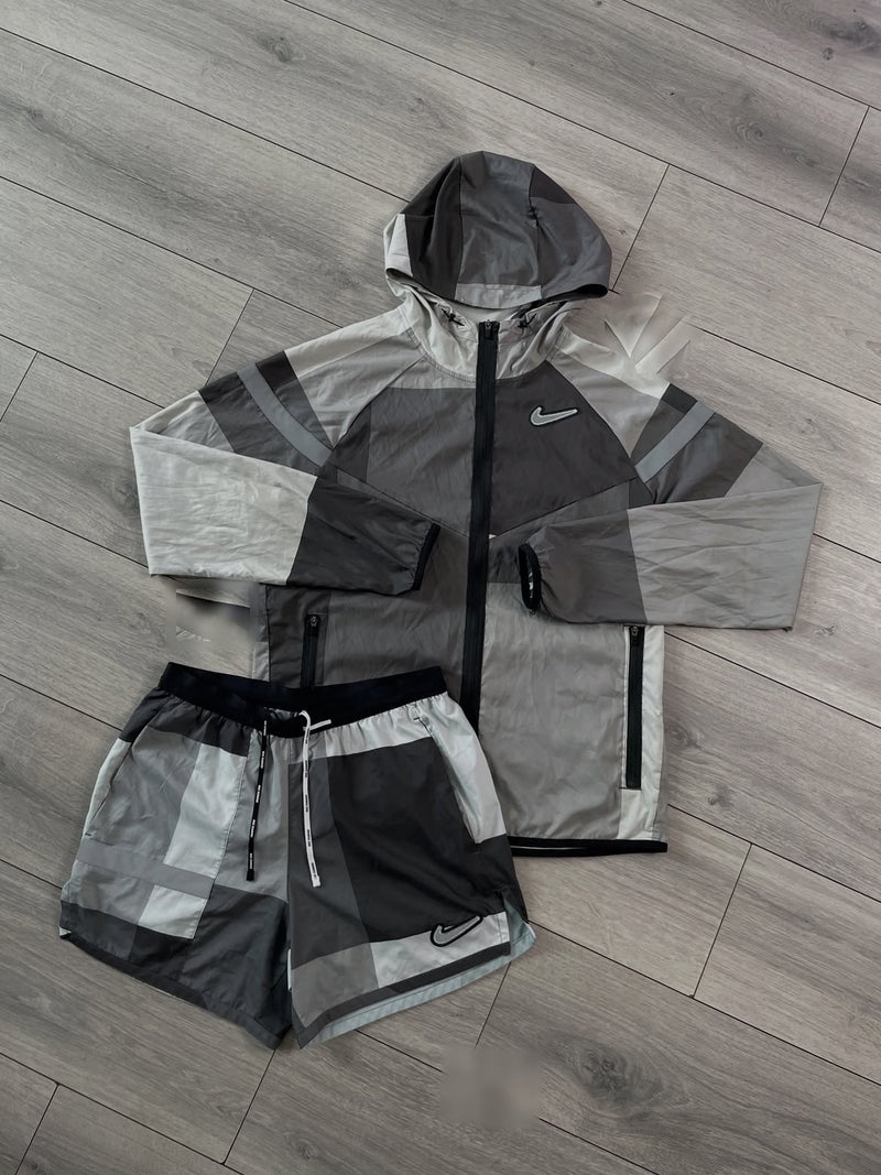 Veste coupe-vent Nike gris anthracite et blanc dépliée avec son short, vue de dessus