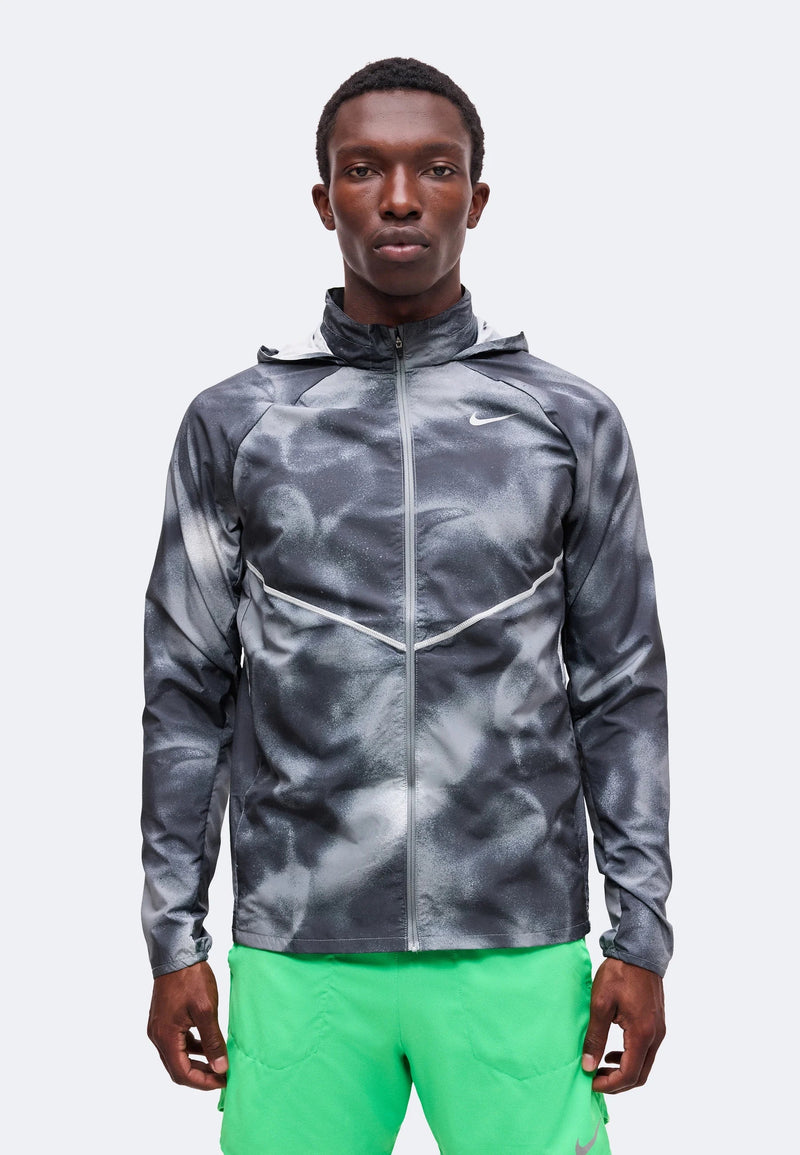 Veste Nike Windrunner grise imprimée portée de face, col zippé et chevron réfléchissant