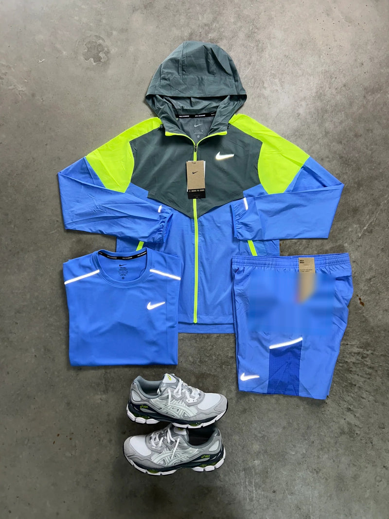 Ensemble running Nike 3 pièces bleu ciel vu d'ensemble à plat : veste coupe-vent à capuche anthracite et volt, t-shirt et short assortis