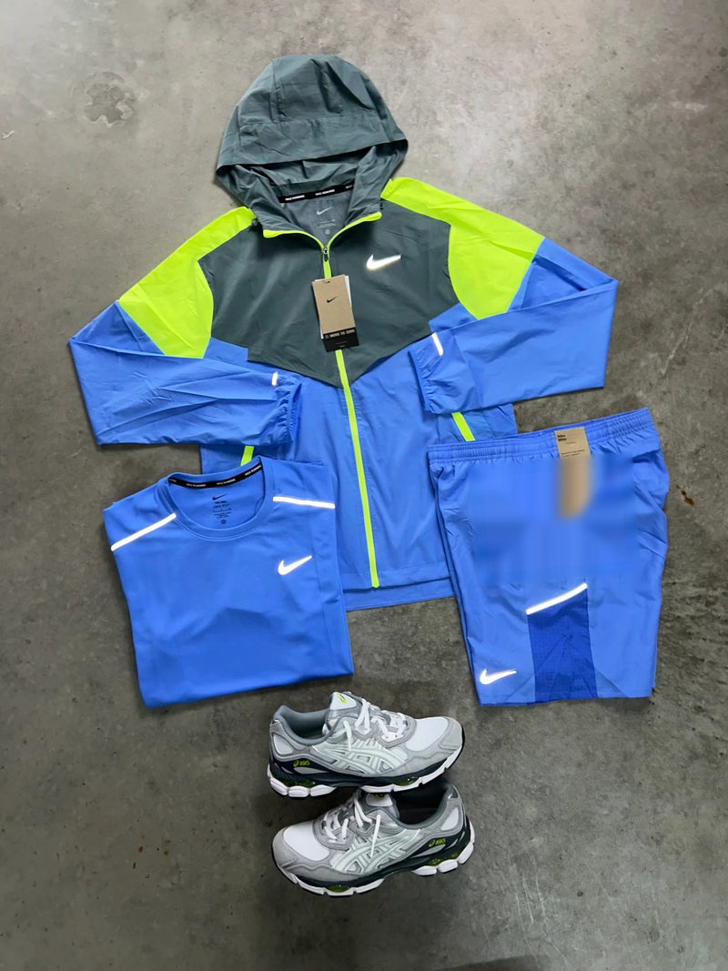 Ensemble running Nike 3 pièces bleu ciel vu de près : veste à capuche ouverte, t-shirt plié et short à poche zippée