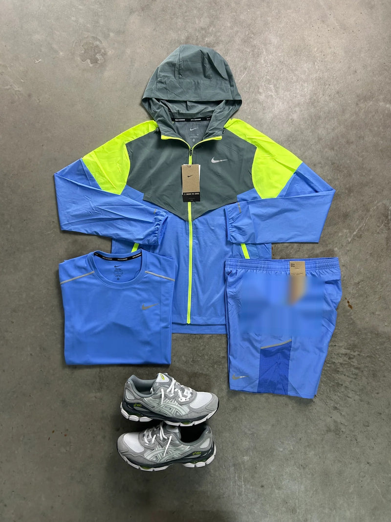 Ensemble running Nike 3 pièces bleu ciel : veste à capuche, t-shirt et short posés à plat avec une paire de baskets