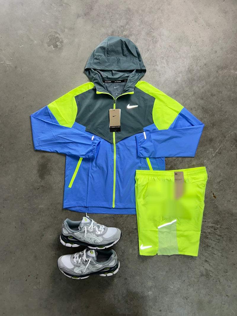 Ensemble running Nike 2 pièces bleu et volt vu d'ensemble à plat : veste coupe-vent colorblock et short assorti