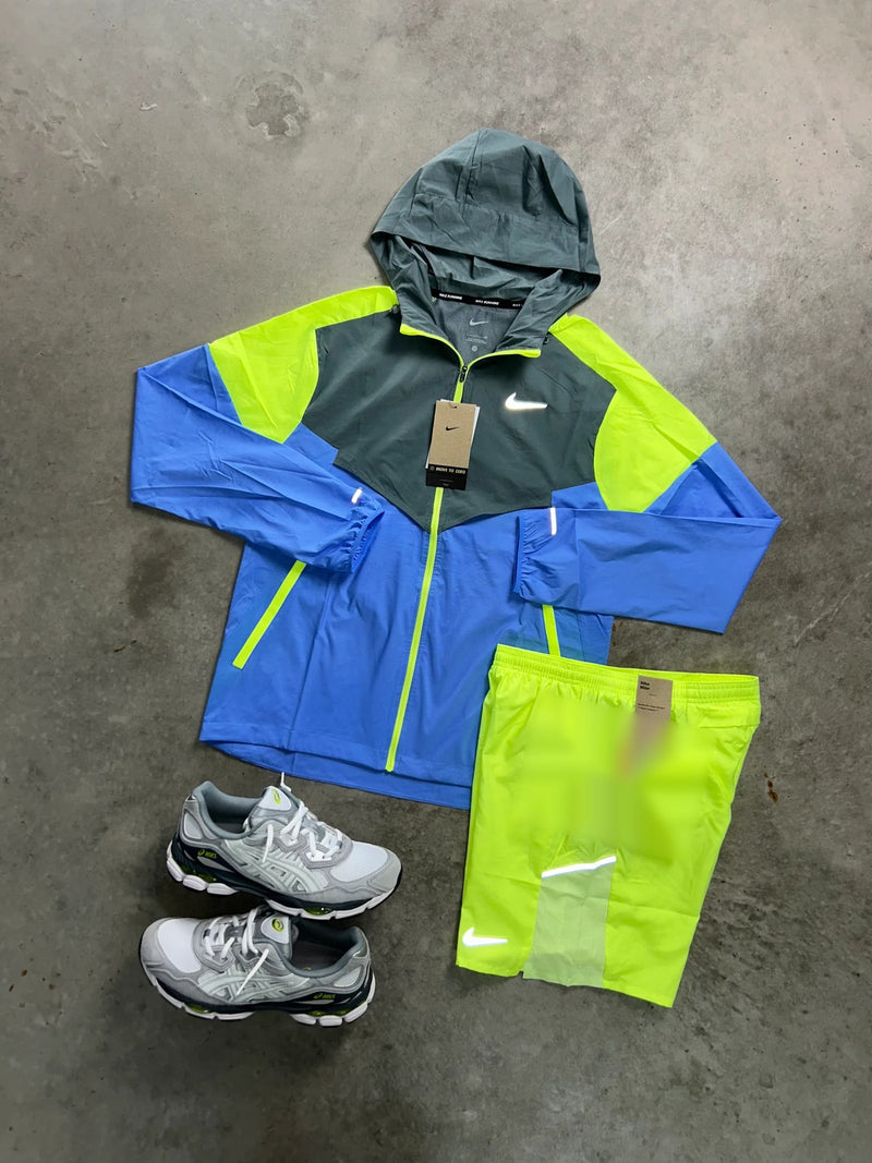 Ensemble running Nike 2 pièces bleu et volt : détail de la veste zippée à capuche anthracite et du short jaune fluo